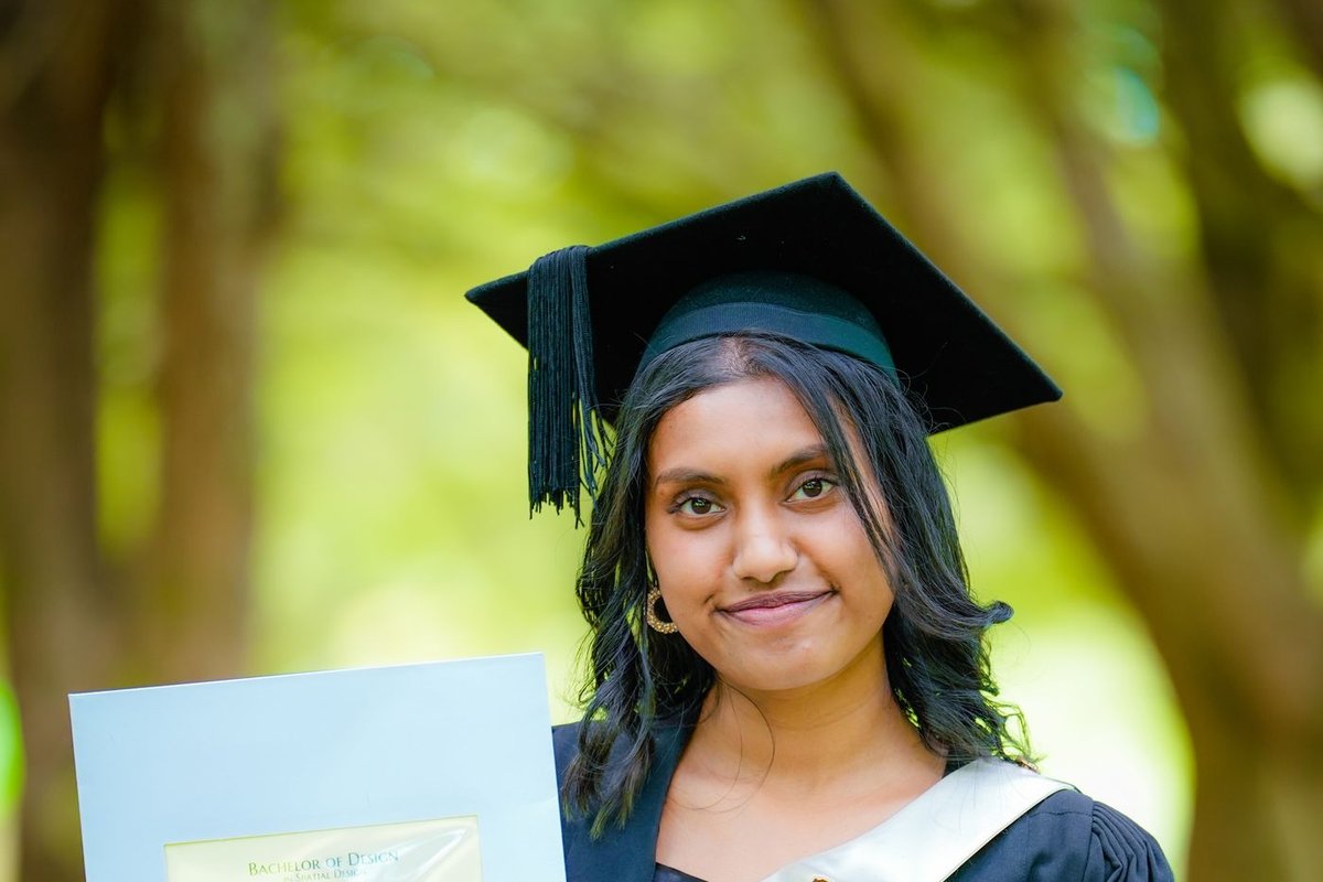 Indian-American graduate in cap and gown holding her degree